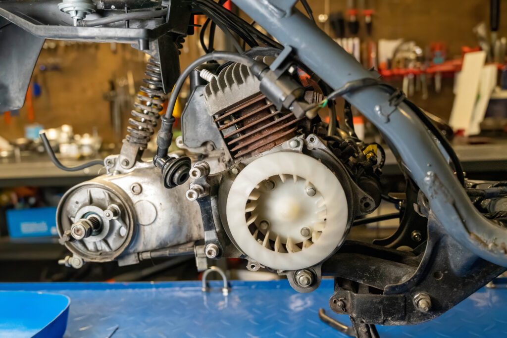 Mechanic repairing motorcycle engine in workshop